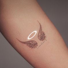 an angel wing tattoo on the right arm and left arm, with a halo above it