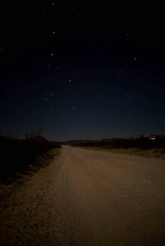 a dirt road at night with stars in the sky