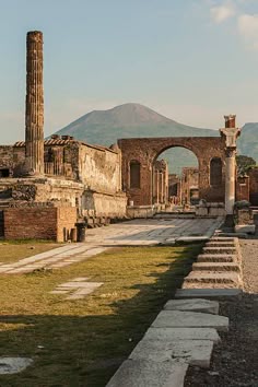 the ruins of an ancient roman city with mountains in the backgrouds and blue sky