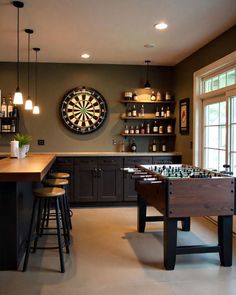 a kitchen with a dart board and darts on the wall next to two bar stools