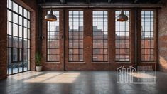 an empty room with large windows and brick walls