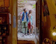 a man and woman are standing in an open doorway looking at each other while the light shines on them