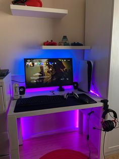 a desk with a computer and headphones sitting on it's side, lit up by purple lighting