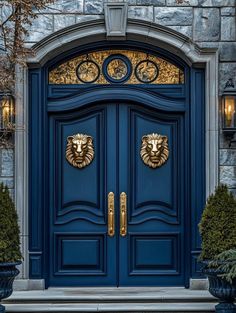 a blue door with two lion heads on it's side and some planters