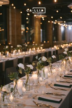 a long table is set with candles and flowers in glass vases, along with place settings