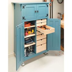 a blue cabinet with drawers and tools in the bottom drawer is open to reveal an assortment of items