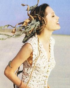 a woman standing in the sand with her hands on her hips and wearing a white top