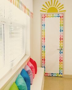 colorful pillows are lined up in front of a white door with the sun painted on it