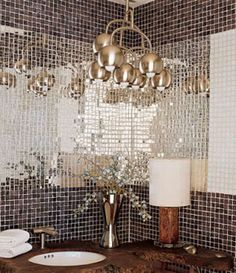a bathroom sink sitting under a chandelier in front of a mirror covered wall