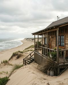 an old wooden cabin on the beach with stairs leading up to it
