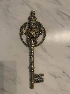 an antique key with a face on it is sitting on a marble countertop in front of a white marble wall