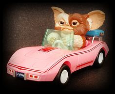 a pink toy car with an elephant in the passenger seat, on a black surface