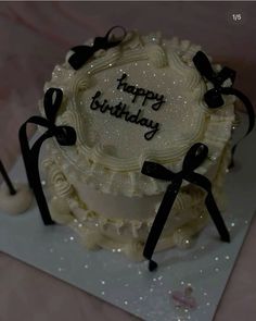 a birthday cake with white frosting and black bows