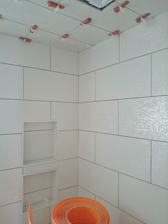 a room with white tiles and an orange hose