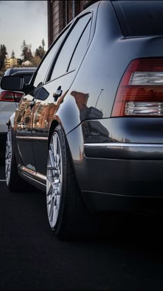 two cars parked next to each other in a parking lot with the back lights on