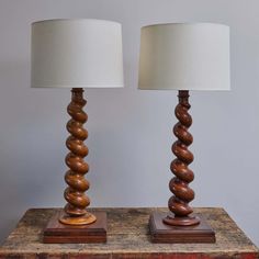 two wooden lamps sitting next to each other on top of a table with a white lamp shade