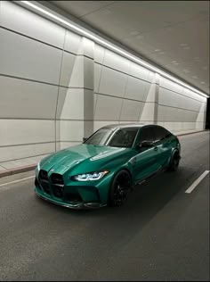 a green sports car parked in front of a white wall with black rims on it