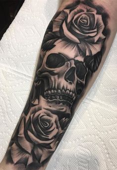 a skull and roses tattoo on the arm