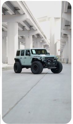 a green jeep parked in an empty parking lot next to a white building with columns