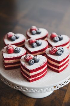 red, white and blue desserts are arranged on a cake platter with raspberries