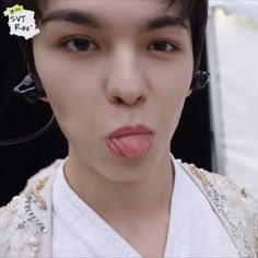 a young man sticking out his tongue and wearing headphones on top of his head