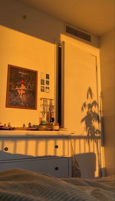 a bedroom with a bed and dresser next to a painting on the wall above it