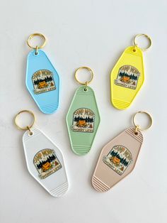 four key chains with different colored tags on them, one has an image of a camper and the other is a bear