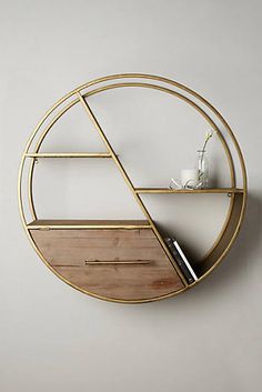 a round shelf with shelves and a vase on it in front of a white wall