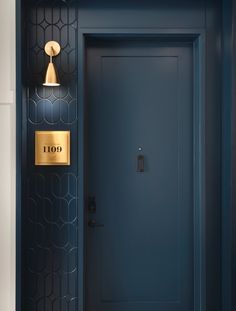a blue door with a gold light on the side and a black wall behind it