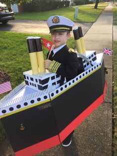 a little boy in a fake boat made to look like a ship with flags on it