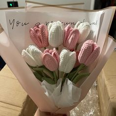 a bouquet of pink and white crocheted tulips is wrapped in paper