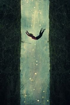 a person floating in the air between two tall grass pillars with water droplets on them