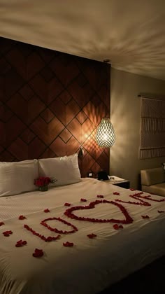 a bed with rose petals on it and the word love spelled out in the middle