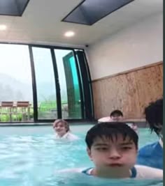several people are in the swimming pool and one person is looking at the camera while others look on