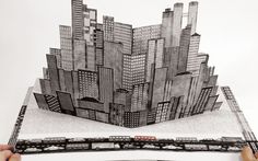 a person holding up a drawing of a cityscape in front of a white background