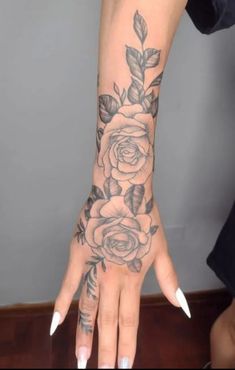 a woman's hand with tattoos on it and flowers in the middle of her arm
