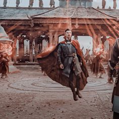 two men dressed in medieval costumes are walking through a courtyard with fire coming from their hands