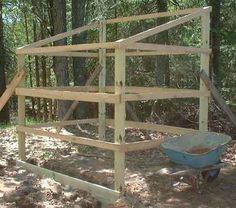 a wooden structure in the woods with a wheelbarrow on it's side