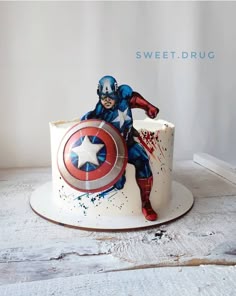 a captain america cake with splattered paint on it and the image of a man holding a shield