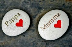 two white rocks with red hearts and the words papa mama written on them are placed next to each other