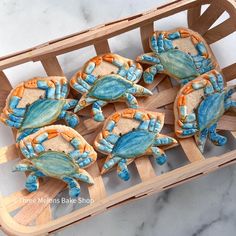 blue and orange crab cookies sitting on top of a wooden tray