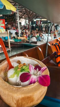 a wooden bowl filled with fruit and flowers on top of a table next to people