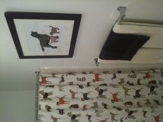a shower curtain with dogs on it next to a towel rack and toilet paper roll