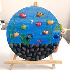there is a painting on the table with rocks in it and fish swimming around them