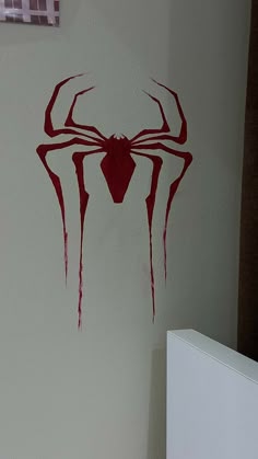 a white toilet sitting next to a wall with a red spider logo painted on it