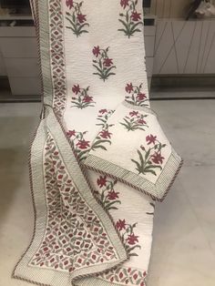 a white quilt with red flowers and green leaves on it, sitting on top of a kitchen counter