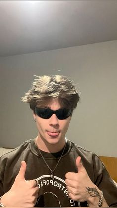 a young man wearing sunglasses giving the thumbs up