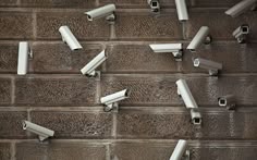 several security cameras on the side of a brick wall, all connected to each other