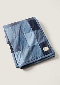 a blue and black checkered blanket laying on top of a white surface with a tag in the middle