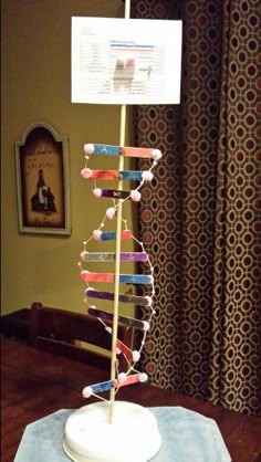 a wooden table topped with a white vase filled with colorful pencils next to a window